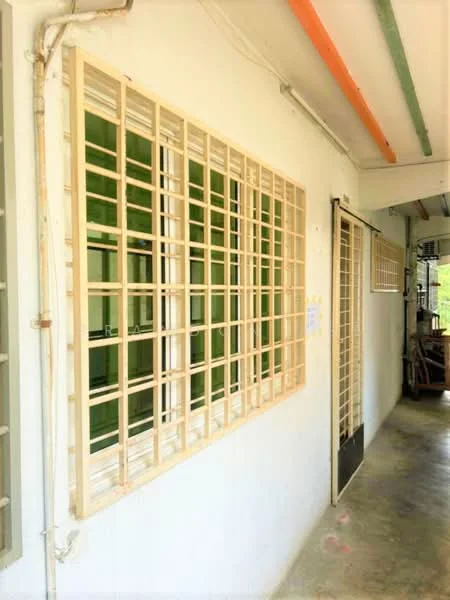 Exterior type: low-rise apartment block; features: white painted facade, grilled windows, green window frames, concrete flooring, exposed pipes, corridor access, natural light from windows; style: modern.
