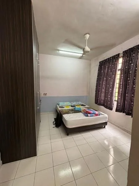 Bedroom features: queen-size bed with colorful bedding, built-in wardrobe with dark wood finish, white tiled flooring, ceiling fan, two windows with dark patterned curtains, plain white walls, overhead fluorescent lighting.
