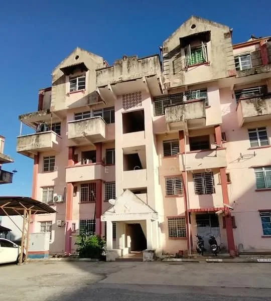 Exterior type: low-rise apartment block; features: pink painted facade, balconies on upper floors, exposed concrete elements, multiple windows with metal grilles, main entrance with awning, parking area in front, air conditioning units visible, two-storey building, surrounded by open space; style: traditional.