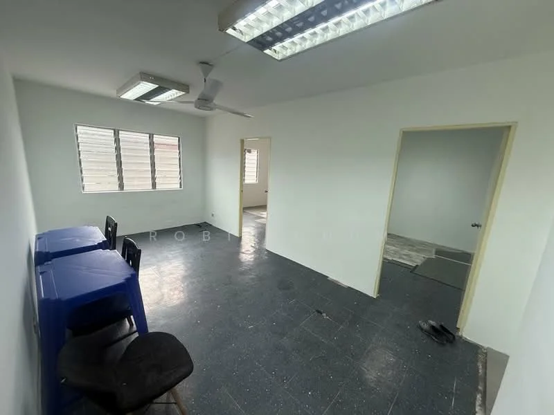 Room features: white painted walls, black vinyl flooring, fluorescent ceiling lights, ceiling fan, two windows with horizontal blinds, two blue plastic tables, black chair, doorway leading to another room; style: minimalist.