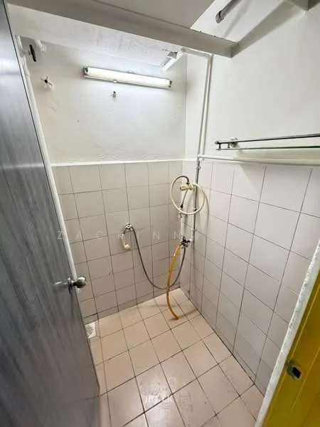 Bathroom features: white tiled walls, light beige tiled flooring, shower area with handheld shower, wall-mounted shower hose, drain on floor, overhead fluorescent light, glass shower partition, shelf above shower area; style: minimalist.