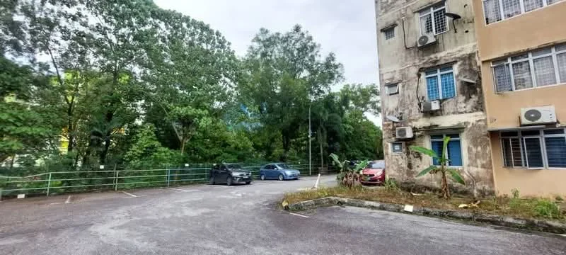 Exterior type: low-rise apartment block; features: exposed concrete facade, multiple wall-mounted split AC units, parking lot, surrounded by mature greenery, trees in the vicinity, two visible parked cars; style: traditional.