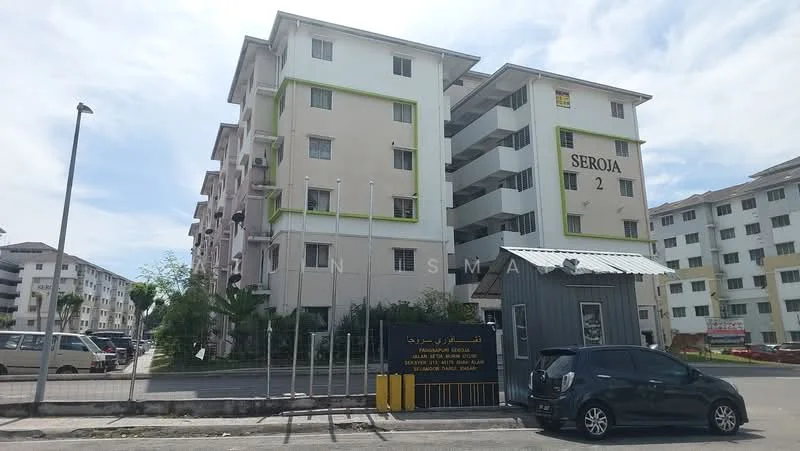 Exterior type: low-rise apartment block; features: cream painted facade, green accent trim, 4-storey building, guard house at entrance, parking lot, surrounded by greenery, signage visible on building; style: modern.