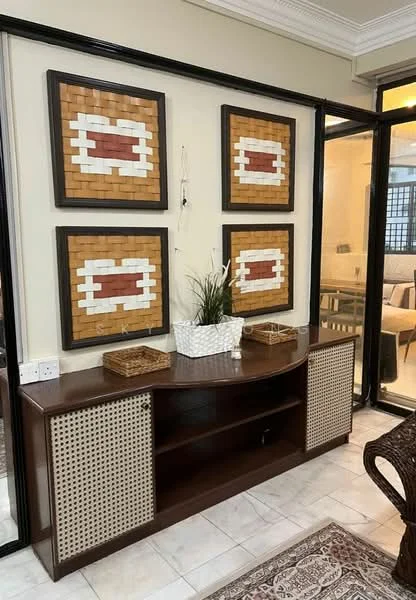 Room features: wooden console table with decorative storage, three framed wall art pieces with woven patterns, white planter with green plant, marble flooring, neutral wall color, glass partition separating rooms, decorative basket on console table, intricate rug on floor; style: modern.