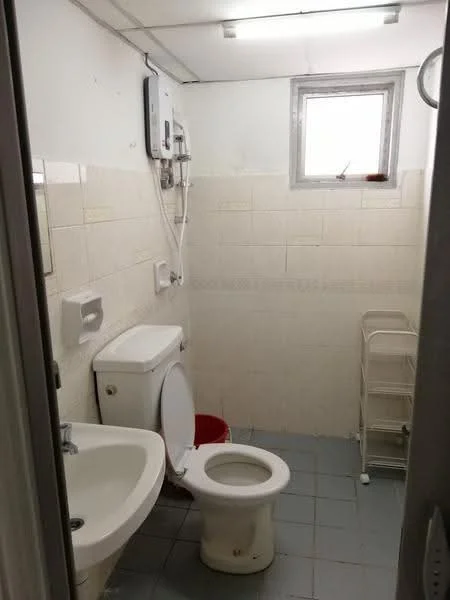 Bathroom features: white tiled walls, grey tiled flooring, one-piece toilet, sink with pedestal, shower with wall-mounted faucet, mirror above sink, toilet paper holder, towel rack, small storage rack, window for natural light, water heater mounted on wall.