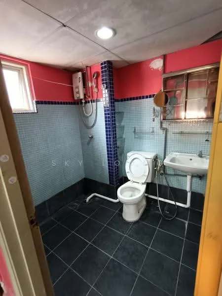 Bathroom features: white toilet, wall-mounted shower with water heater, sink with chrome faucet, blue tiled walls, grey floor tiles, window for natural light, mirror, shower head, exposed plumbing.