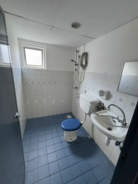 Bathroom features: white tiled walls, blue tiled flooring, one-piece toilet, chrome basin mixer faucet, sink with integrated countertop, shower with handheld showerhead, small window for natural light, mirror above sink, ceiling light fixture.