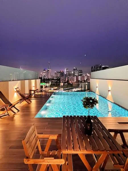 Exterior type: high-rise condominium; features: infinity pool, pool deck with loungers, city skyline view, wooden decking, outdoor dining table, decorative potted plant, night lighting, glass railing; style: modern.