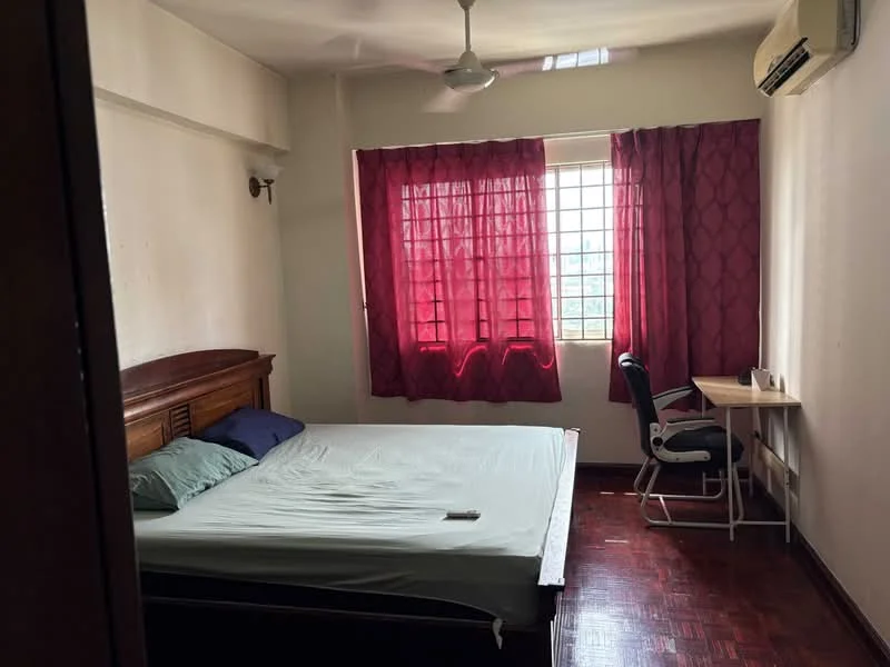 Bedroom features: queen-size bed, wooden bed frame, green bedding, two pillows, desk with chair, window with sheer curtains, red curtains, wall-mounted air conditioning unit, ceiling fan, wooden flooring.