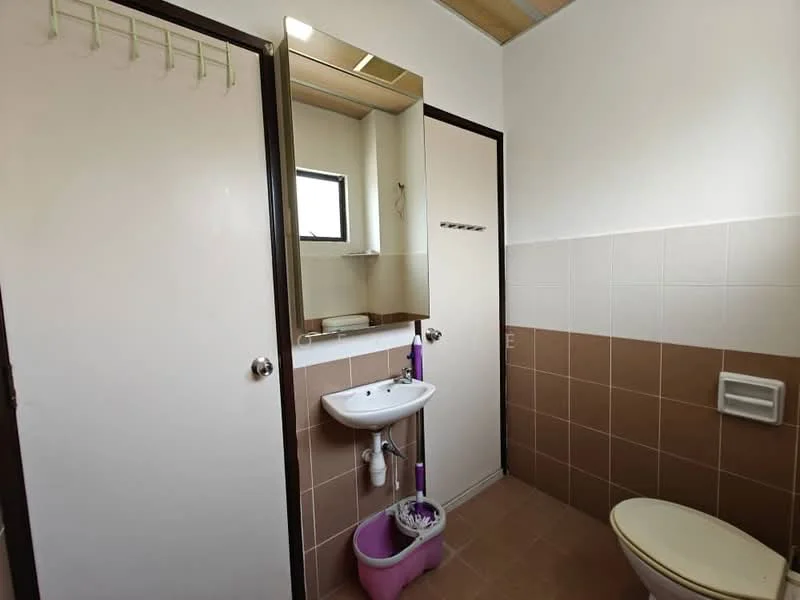 Bathroom features: white painted walls, brown tiled walls, ceramic tile flooring, single-sink vanity with mirror, toilet, window for natural light, towel hooks, purple toilet brush holder.
