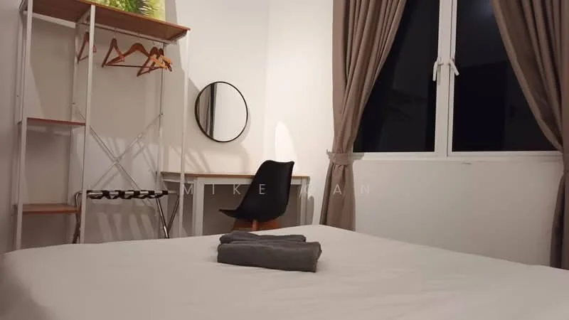 Bedroom features: queen-size bed with white bedding, wooden headboard, grey towel folded on bed, white walls, curtains in light brown, floor-to-ceiling window, black chair, wooden desk, round mirror, clothes rack with hangers, open shelving unit; style: modern.