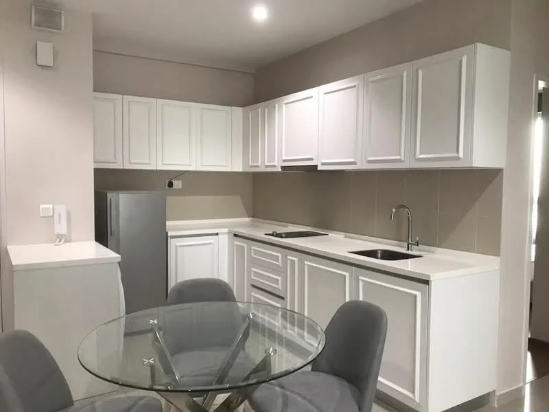 Kitchen features: white shaker cabinets, stainless-steel fridge, single-bowl stainless-steel sink, chrome pull-down faucet, white quartz countertop, ceramic tile backsplash, built-in oven, 4-burner gas hob, glass dining table, upholstered dining chairs, recessed LED downlights, cream painted walls, tile flooring; style: modern.