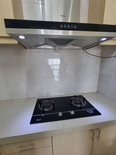 Kitchen features: stainless-steel range hood, 2-burner gas hob, white tiled backsplash, light-colored cabinetry, countertop with light finish, under-cabinet lighting; style: modern.