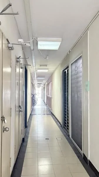 Hallway features: white painted walls, tile flooring, ceiling lights, metal doors, glass sliding doors, bicycle parked, corridor with windows, neutral color scheme.