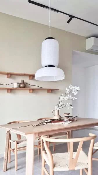 Dining features: light wood dining table, 4 wooden dining chairs, white pendant lamp, shelf with decorative items, neutral painted walls, air conditioning unit, decorative vase with flowers, minimalist decor; style: minimalist.