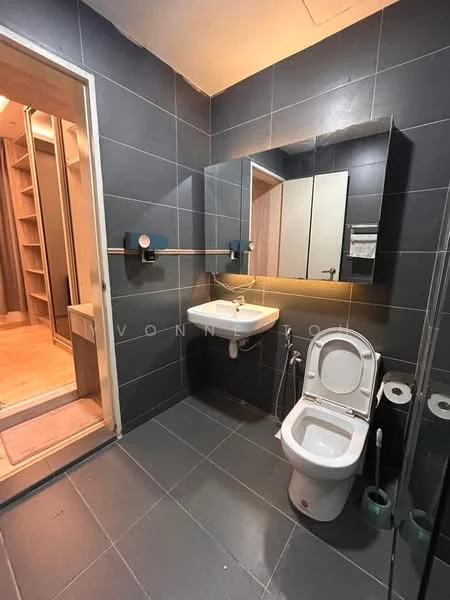 Bathroom features: grey tiled walls, grey tiled flooring, wall-mounted sink, chrome basin mixer faucet, framed mirror, two-door cabinet, one-piece toilet, toilet paper holder, towel rail, glass shower enclosure, shower head, built-in shelving; style: modern.