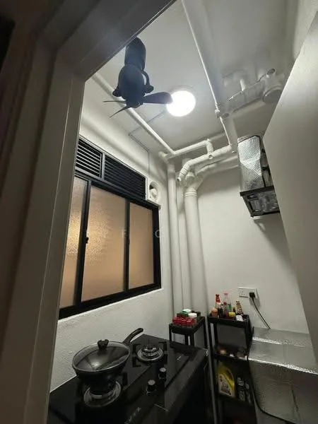 Kitchen features: black countertop, stainless-steel gas stove with 2 burners, exhaust fan, wall-mounted shelving unit, silver storage containers, window with frosted glass, white painted walls, ceiling light, ceiling-mounted pipes, black cart with storage; style: modern.