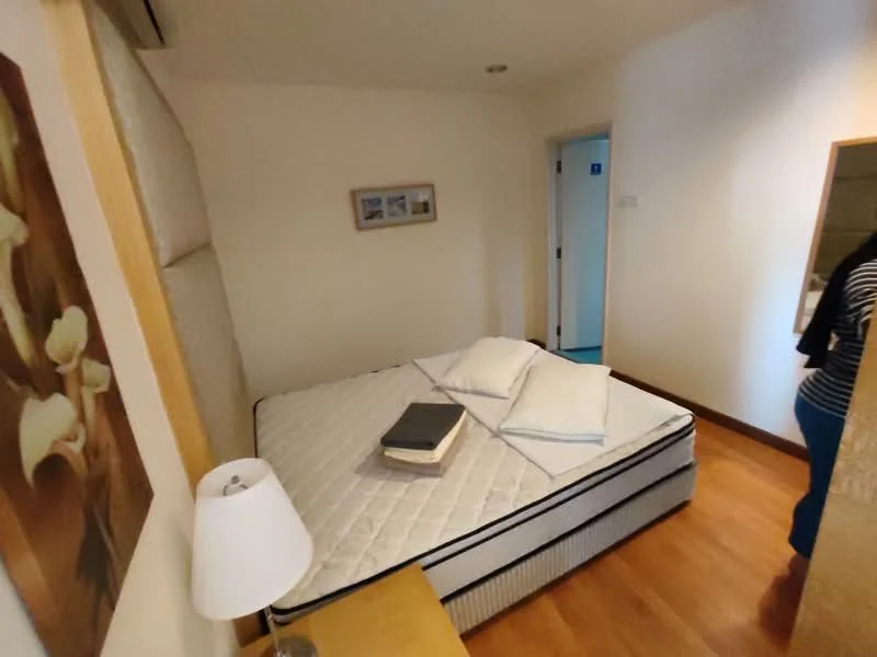 Bedroom features: queen-size bed, wooden flooring, white painted walls, framed artwork on wall, bedside lamp, nightstand, mirror on wall, two pillows, book on bed; style: modern.