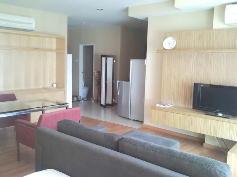 Living features: grey fabric sofa, red upholstered armchair, glass-top dining table, wooden TV console, wall-mounted TV, refrigerator, air conditioning unit, laminate flooring, light beige painted walls, decorative wall clock; style: modern. Room features: open layout, doorway leading to another room.