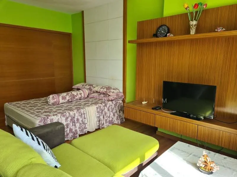 Living features: green painted walls, wood paneling, queen-size bed with floral bedding, wooden wall-mounted shelf, flat-screen TV on wooden console, sofa in light green fabric, decorative vase with flowers, area rug, natural light from window; style: modern.