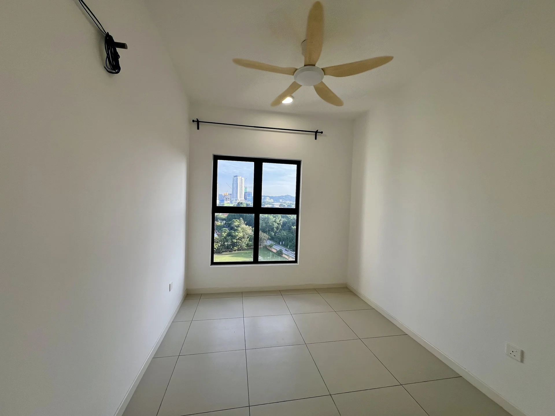 Room features: white painted walls, ceiling fan, large window with black frame, neutral tile flooring, view of greenery, view of city skyline; style: modern; view: city.