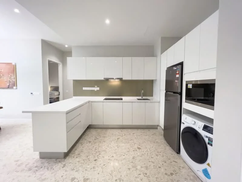 Kitchen features: white flat-panel cabinets, marble countertop, single-bowl stainless-steel sink, chrome pull-down faucet, built-in oven, freestanding range oven, stainless-steel fridge, built-in microwave, front-load washing machine, recessed downlights, tile flooring, neutral wall colour, open layout; style: modern.