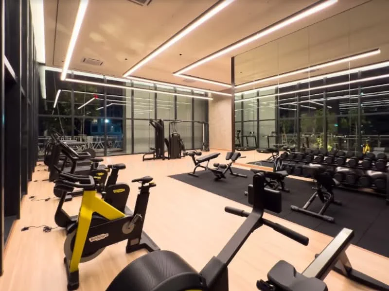 Room features: large floor-to-ceiling windows, mirrored wall, wooden flooring, black rubber flooring, various gym equipment, weightlifting bench, free weights, exercise bikes, treadmill, cardio machines, LED strip lighting, recessed ceiling lights; style: modern; view: city.