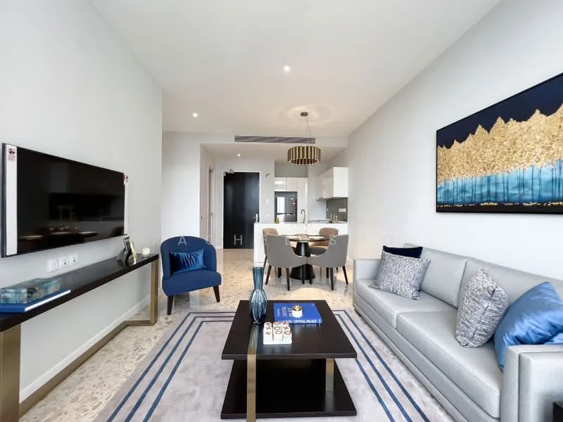Living features: grey fabric sofa, blue accent pillows, glass coffee table with gold frame, wall-mounted TV, decorative artwork with gold and blue tones, recessed ceiling lights, neutral wall color, textured area rug, dining table with four chairs, open layout to kitchen, floor-to-ceiling windows, light-colored flooring; style: modern.