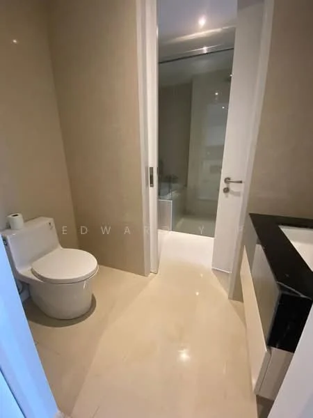 Bathroom features: one-piece toilet, white ceramic toilet, wall-mounted sink, black countertop, cream tiled walls, cream tiled flooring, mirror, glass shower enclosure; style: modern.