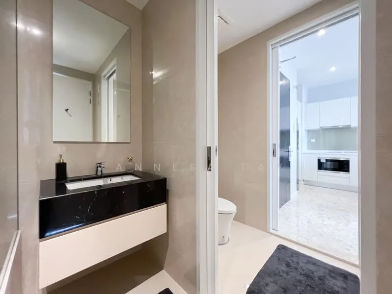 Bathroom features: black countertop with sink, single-bowl sink, wall-mounted faucet, mirror above sink, light-colored cabinetry, toilet, tile flooring, neutral wall tiles, recessed lighting, sliding glass door, towel mat; style: modern. Room features: kitchen cabinetry visible, white appliances visible, open layout.