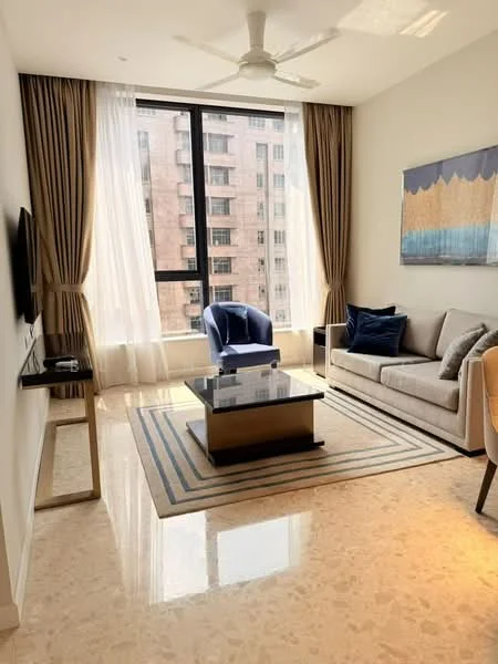 Living features: marble flooring, floor-to-ceiling windows, sheer curtains, 3-blade ceiling fan, sofa in light grey fabric, blue accent chair, coffee table with black surface, area rug with geometric pattern, wall-mounted TV, decorative artwork on wall; style: modern; view: city.