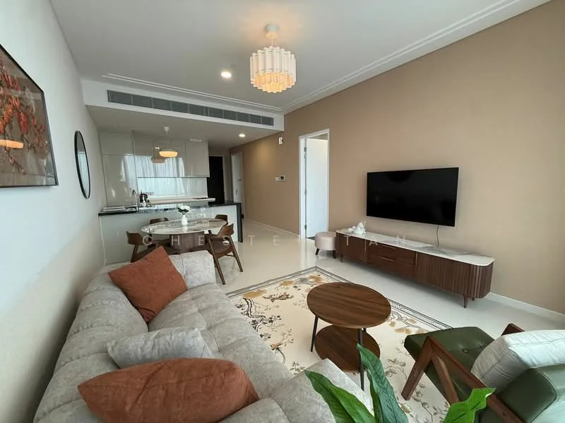 Living features: 3-seater fabric sofa in light grey, orange throw pillows, wooden coffee table, TV console, wall-mounted TV, area rug with floral pattern, green indoor plant, chandelier with multiple bulbs, recessed downlights, cream painted walls, white ceiling, large window with sheer curtains; style: modern. Kitchen features: black countertop, stainless-steel sink, built-in oven, freestanding range oven, microwave, kitchen cabinetry, bar stools, open layout to living area; style: modern.