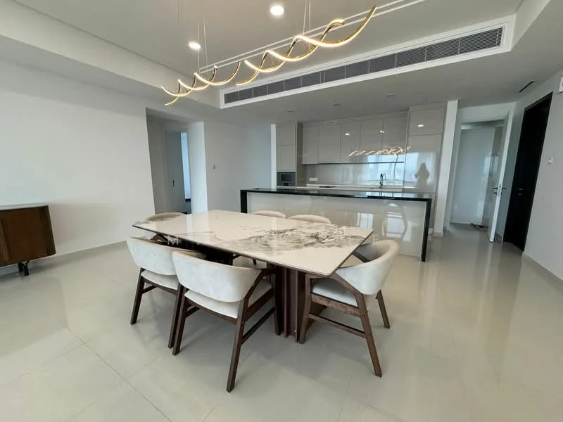 Dining features: 6-seater dining table with marble top, upholstered dining chairs in cream, pendant lighting above dining table, white painted walls, light-colored tile flooring, open-plan layout with kitchen visible, kitchen island with bar seating, built-in cabinetry in kitchen, recessed ceiling lights; style: modern. Kitchen features: white cabinetry, black countertop, built-in oven, stainless-steel fridge, induction cooktop, microwave, open shelving, sink with faucet; style: modern.