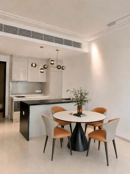 Dining features: round dining table, 4 upholstered dining chairs in beige and orange, pendant lighting with spherical bulbs, white walls, light-colored flooring, kitchen island with bar seating, stainless-steel sink, modern faucet, decorative plant on table, open layout to kitchen; style: modern. Kitchen features: stainless-steel appliances, grey cabinetry, white countertop, built-in oven, induction cooktop, recessed lighting, ventilation system, minimalist design; style: modern.