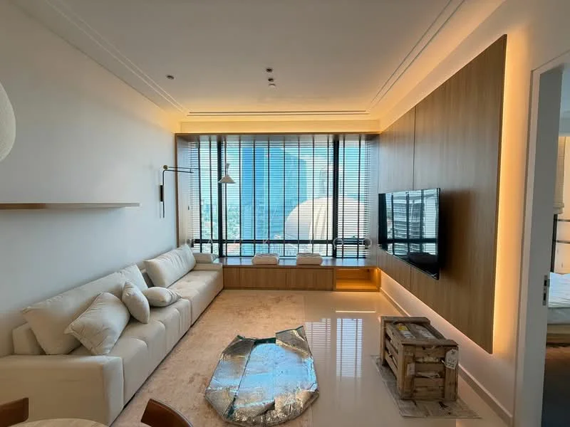 Living features: L-shape sectional sofa in white, coffee table, wall-mounted TV, wood panel feature wall, recessed lighting, floor-to-ceiling windows, sheer curtains, light-colored carpet flooring, decorative wall sconce, built-in cabinetry below TV; style: modern; view: city.