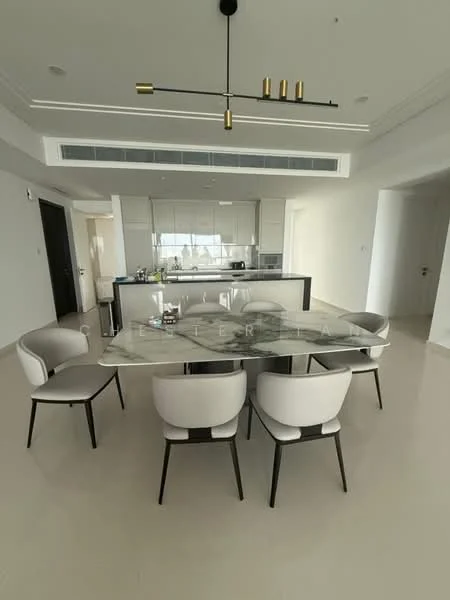 Dining features: 6-seater dining table with marble top, upholstered dining chairs in light color, pendant light fixture with multiple bulbs, open-plan layout connecting to kitchen, light-colored walls, polished tile flooring, large windows allowing natural light, minimalist decor; style: modern. Kitchen features: kitchen island with bar seating, stainless-steel appliances, white cabinetry, glass backsplash, built-in oven, refrigerator, cooktop, hood vent; style: modern.