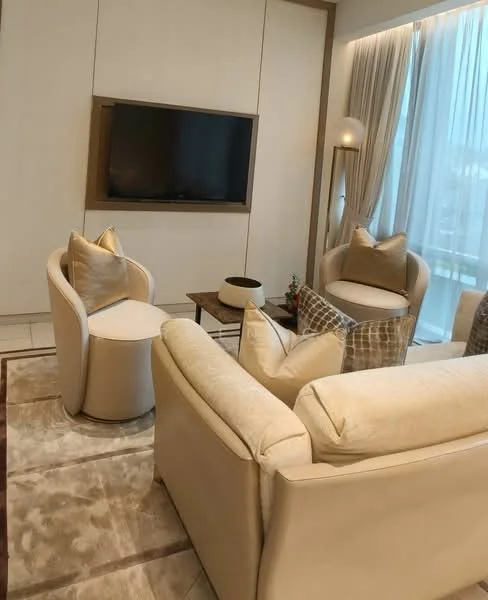 Living features: beige fabric sofa, two accent chairs with cushions, wooden coffee table, wall-mounted TV, light-colored area rug, floor-to-ceiling windows with sheer curtains, decorative floor lamp, neutral painted walls, wood paneling, decorative throw pillows; style: modern.