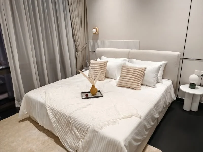 Bedroom features: king-size bed with upholstered headboard, white bedding with textured throw, decorative pillows in beige, bedside table with lamp, floor lamp, curtains in light fabric, neutral wall color, carpet flooring in beige; style: modern.
