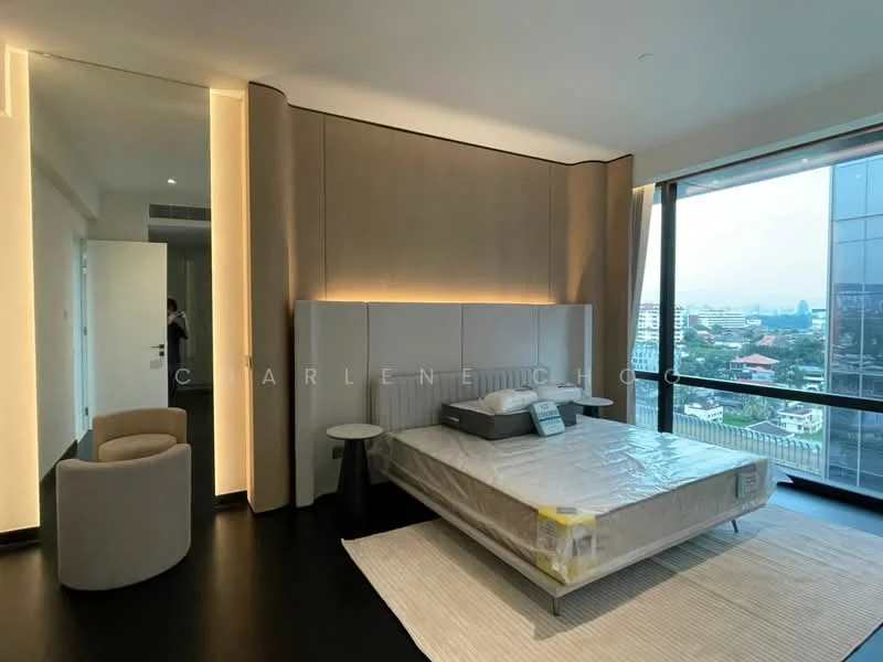 Bedroom features: king-size bed with upholstered headboard, nightstands on either side of the bed, floor-to-ceiling windows, city view, light wood paneling on walls, recessed lighting, dark wood flooring, area rug, minimalist armchair; style: modern; view: city.