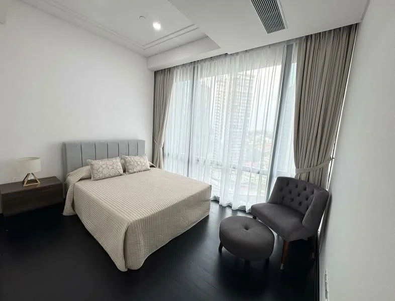 Bedroom features: king-size bed with upholstered headboard, beige bedspread, two decorative pillows, nightstand with lamp, grey accent chair, ottoman, floor-to-ceiling windows, sheer curtains, dark wood flooring, recessed ceiling lights, city view; style: modern; view: city.