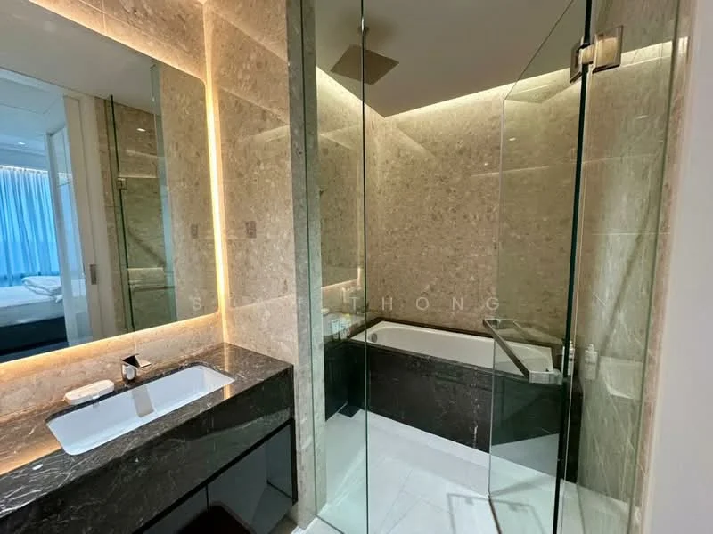 Bathroom features: marble wall cladding, glass shower enclosure, freestanding bathtub, single-sink vanity with black cabinet, chrome basin mixer faucet, backlit mirror, recessed LED lighting, grey stone countertop; style: modern.