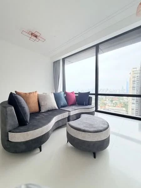 Living features: curved sectional sofa in grey fabric, decorative cushions in various colors, large floor-to-ceiling windows, city skyline view, minimalist ceiling light fixture, white painted walls, light-colored flooring, neutral color palette; style: modern; view: city.