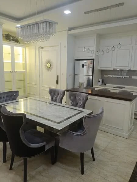 Dining features: marble dining table, 4 upholstered dining chairs in grey, chandelier with crystal accents, cream painted walls, tile flooring, built-in cabinetry with glass doors, stainless-steel fridge, kitchen island with countertop, recessed lighting, decorative wall mirror; style: modern. Kitchen features: white cabinetry, countertop with bar seating, built-in oven, stainless-steel appliances, kitchen sink, kitchen backsplash, under-cabinet lighting; style: modern.