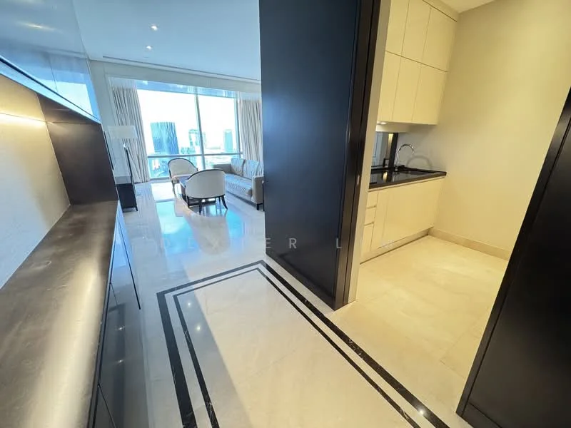 Room features: marble flooring, white painted walls, recessed downlights, kitchen cabinetry in light color, black countertop, floor-to-ceiling windows, curtains, open layout, decorative wall paneling, seating area visible in background; style: modern; view: city.
