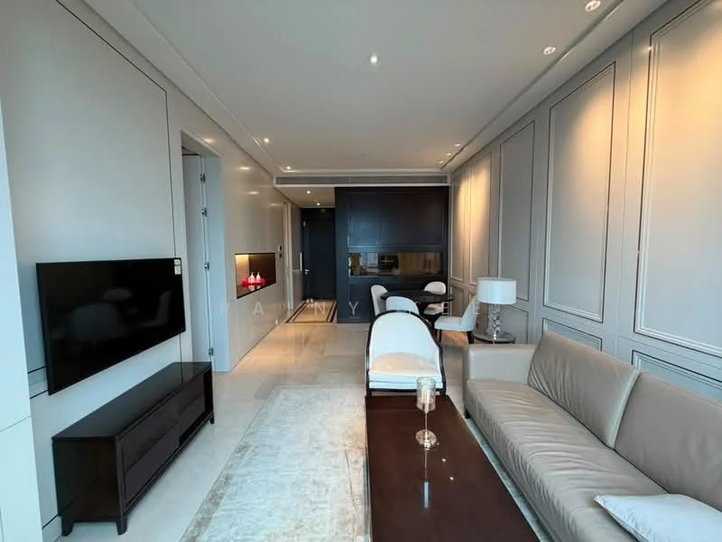 Living features: light grey painted walls, cream marble flooring, recessed downlights, wall-mounted TV, brown leather sofa, wood coffee table, white armchair, decorative wall paneling, fireplace with modern design, glass side table with lamp, area rug with neutral tones; style: modern.