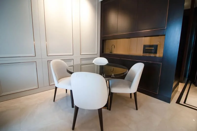 Dining features: round glass dining table, 4 upholstered dining chairs in white, dark wood cabinetry, built-in kitchen counter, microwave, recessed lighting, cream painted walls, marble tile flooring; style: modern.