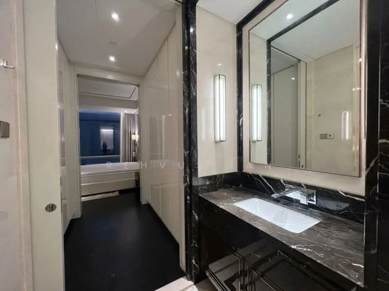 Bathroom features: black marble countertop, single-bowl sink, chrome faucet, framed mirror, wall-mounted lighting, cream painted walls, dark flooring, built-in cabinetry; style: modern. Room features: cream painted walls, dark flooring, doorway leading to bedroom.