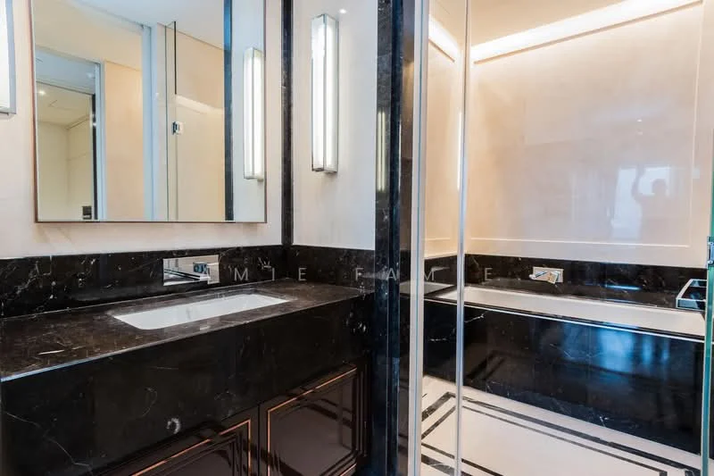 Bathroom features: black marble countertop, single-bowl sink, chrome basin mixer faucet, framed mirror, bathtub, glass shower enclosure, wall-mounted lighting fixtures, tile cladding on walls, dark cabinetry, recessed lighting; style: luxury.