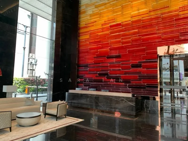 Room features: red and orange accent wall, black marble flooring, sofa with light upholstery, coffee table, decorative area rug, large glass entrance door, reception desk, wall-mounted lighting, potted plants, high ceiling, modern decor; style: modern; view: garden.