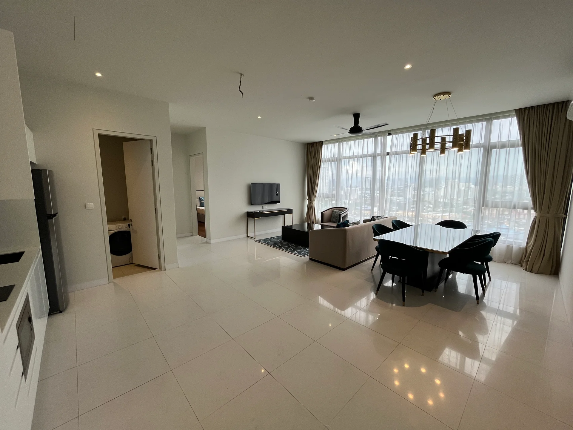 Living features: large floor-to-ceiling windows, grey fabric sofa, black dining table with six chairs, TV mounted on wall, recessed downlights, 5-blade ceiling fan, white walls, polished marble tile flooring, decorative light fixture, area rug with geometric pattern; style: modern; view: city. Room features: open layout, doorway leading to other rooms.